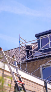 Monteur werkt op de steiger naast een dakkapel in Koudekerke